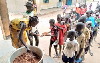 Un volontario serve cibo ai bambini in una scuola nel Sud Sudan.