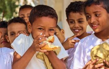 I bambini mangiano cibo in un parco giochi nello Yemen.