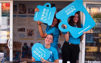 I volontari posano con grandi tazze in un evento di Mary's Meals.