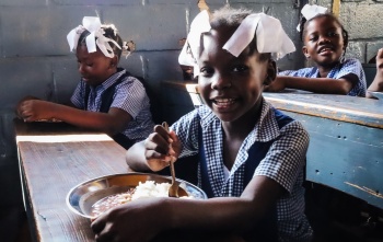 Girls eating Mary's Meals in school