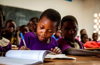 Un giovane bambino prende appunti in classe in Malawi.
