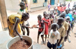 Un volontario serve cibo ai bambini in una scuola nel Sud Sudan.