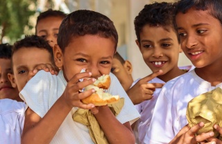 I bambini mangiano cibo in un parco giochi nello Yemen.