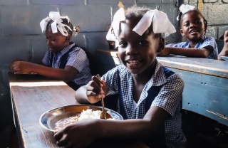 Girls eating Mary's Meals in school