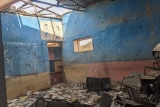 Image of a classroom which has been left ruined after recent conflict. The roof appears to have caved in with debris covering the floor. 