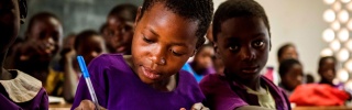 Un giovane bambino prende appunti in classe in Malawi.