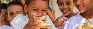 I bambini mangiano cibo in un parco giochi nello Yemen.