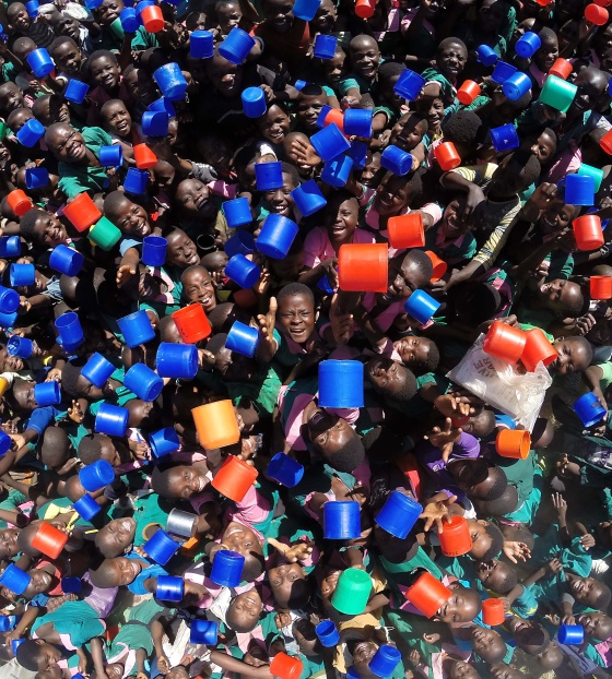 Un grande gruppo di bambini si riunisce a scuola per ricevere i pasti.