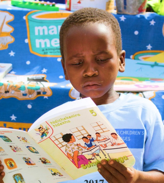 Un giovane ragazzo legge un libro a scuola.