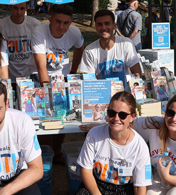 Image of Mary's Meals supporters posing with Mary's Meals props.