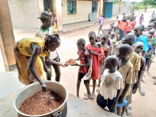 Un volontario serve cibo ai bambini in una scuola nel Sud Sudan.