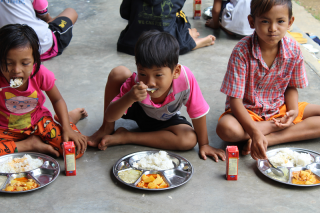 I bambini si siedono insieme per mangiare a scuola in Thailandia.