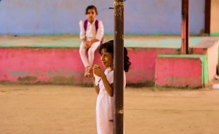 Una giovane ragazza si appoggia a un palo in un parco giochi nello Yemen.