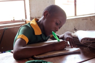 Un giovane bambino prende appunti in classe in una scuola in Zimbabwe.