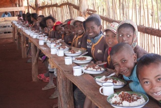 I bambini fanno la fila per essere serviti da mangiare a scuola.