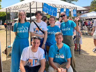 Image of Mary's Meals supporters posing in front of stall.